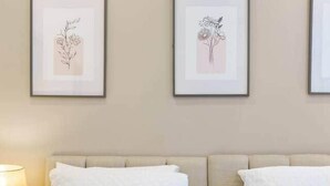 Ein Hotelzimmer mit einem Bett, zwei gerahmten Blumenbildern an der Wand und einem Paar Handtüchern, die auf dem Bett drapiert sind.