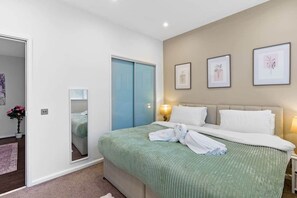 A hotel room with a bed, bedside tables, a mirror, and framed artwork on the wall. - Princes House BN1 1EA (Brighton and Hove)