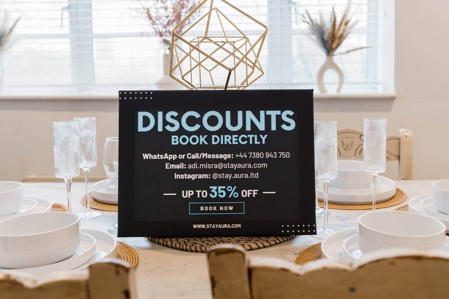 A promotional sign for discounts on a table set with white dinnerware and glasses.