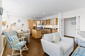 A modern living room with a sofa, a rocking chair, and a dining area with a table and chairs. - Princes House BN1 1EA (Brighton and Hove)