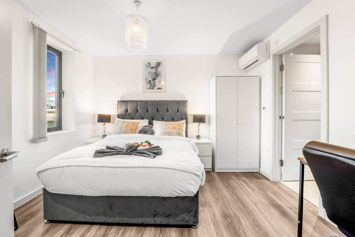 Une chambre moderne avec un grand lit, des lampes de chevet, un lustre et une armoire.