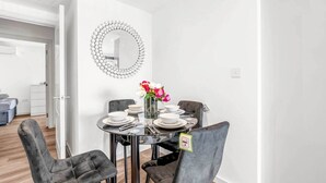 A dining area with a round table, four chairs, and a vase of flowers. - Flat 5, Brentford TW8 9NA (Brentford)