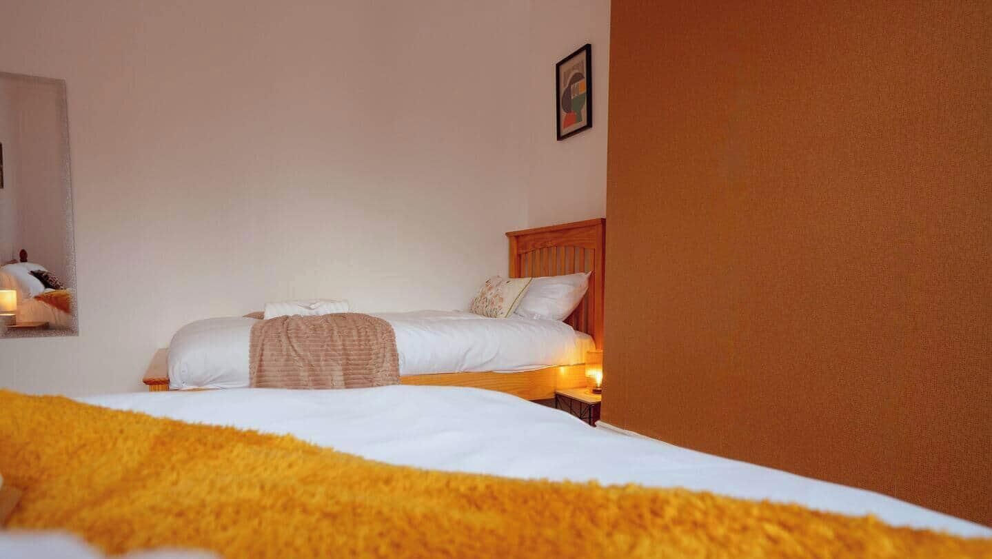Quarto de hotel com cama, mesa de cabeceira e quadro pendurado na parede.
