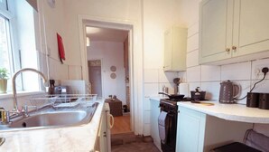 Pieni, käytännöllinen keittiö, jossa on pesuallas, liesi ja kaapit.
