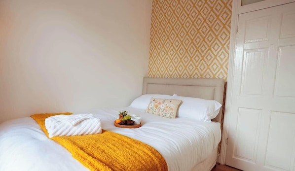 A neatly made bed with white linens, a yellow throw blanket, and a fruit basket on the side. - Gateshead Newcastle, NE8 (Gateshead)