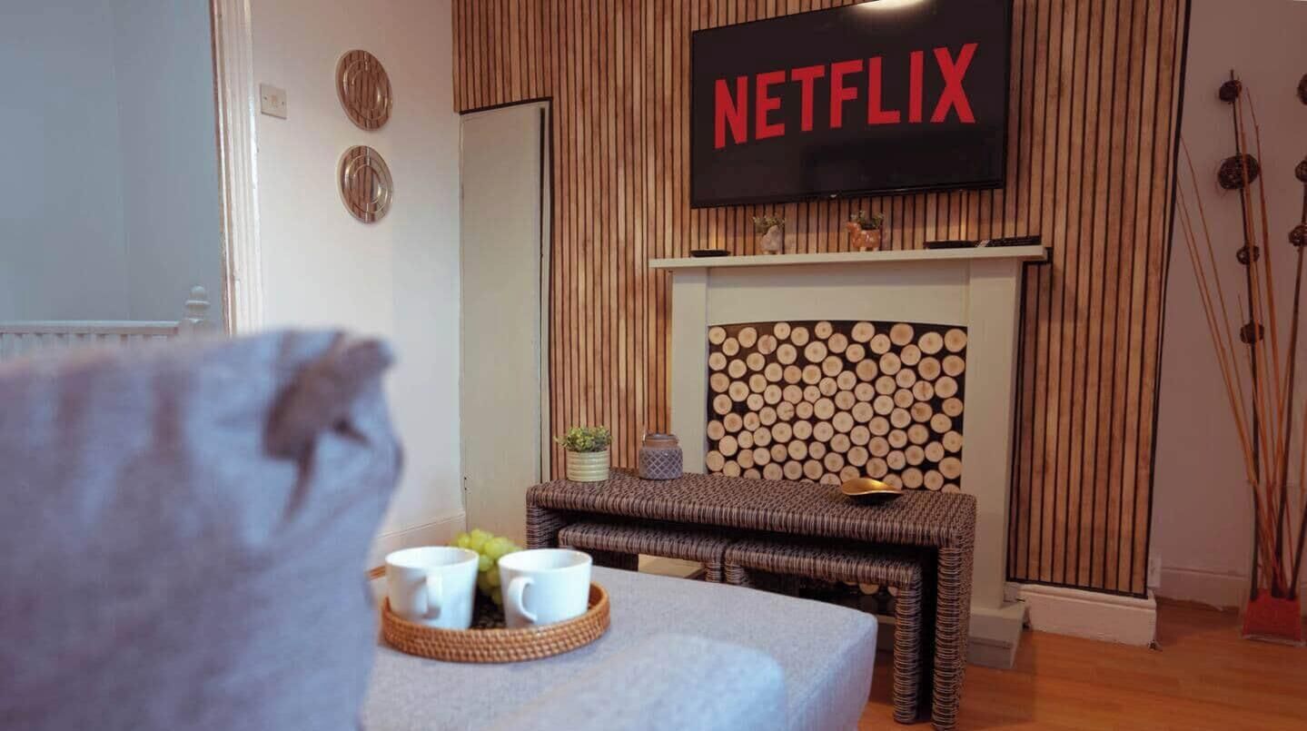 A cozy room with a fireplace, a television mounted above it, and a bed with a bedside table.