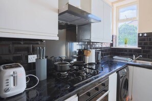 A kitchen with a gas stove, a toaster, and a window with a view of greenery. - Fenham, Newcastle NE4 (Newcastle upon Tyne)