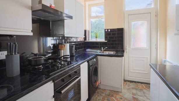 Een functionele keuken met een fornuis, oven en een wasmachine.