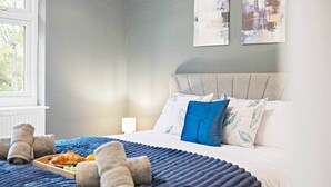 A hotel room with a bed, pillows, a tray with croissants, and towels. - 18 Carrick Gardens, N17 7AX (London)