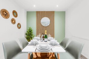 A dining room with a white table set for four, a mirror, and decorative wall panels. - 18 Carrick Gardens, N17 7AX (London)