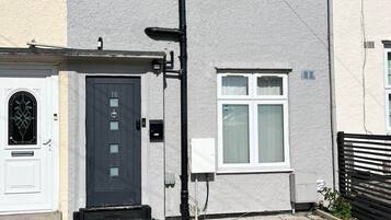 A residential building with a grey facade, a black door with the number 18, and a small window.