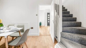 A modern interior with a dining area, a staircase, and a hallway. - 18 Carrick Gardens, N17 7AX (London)
