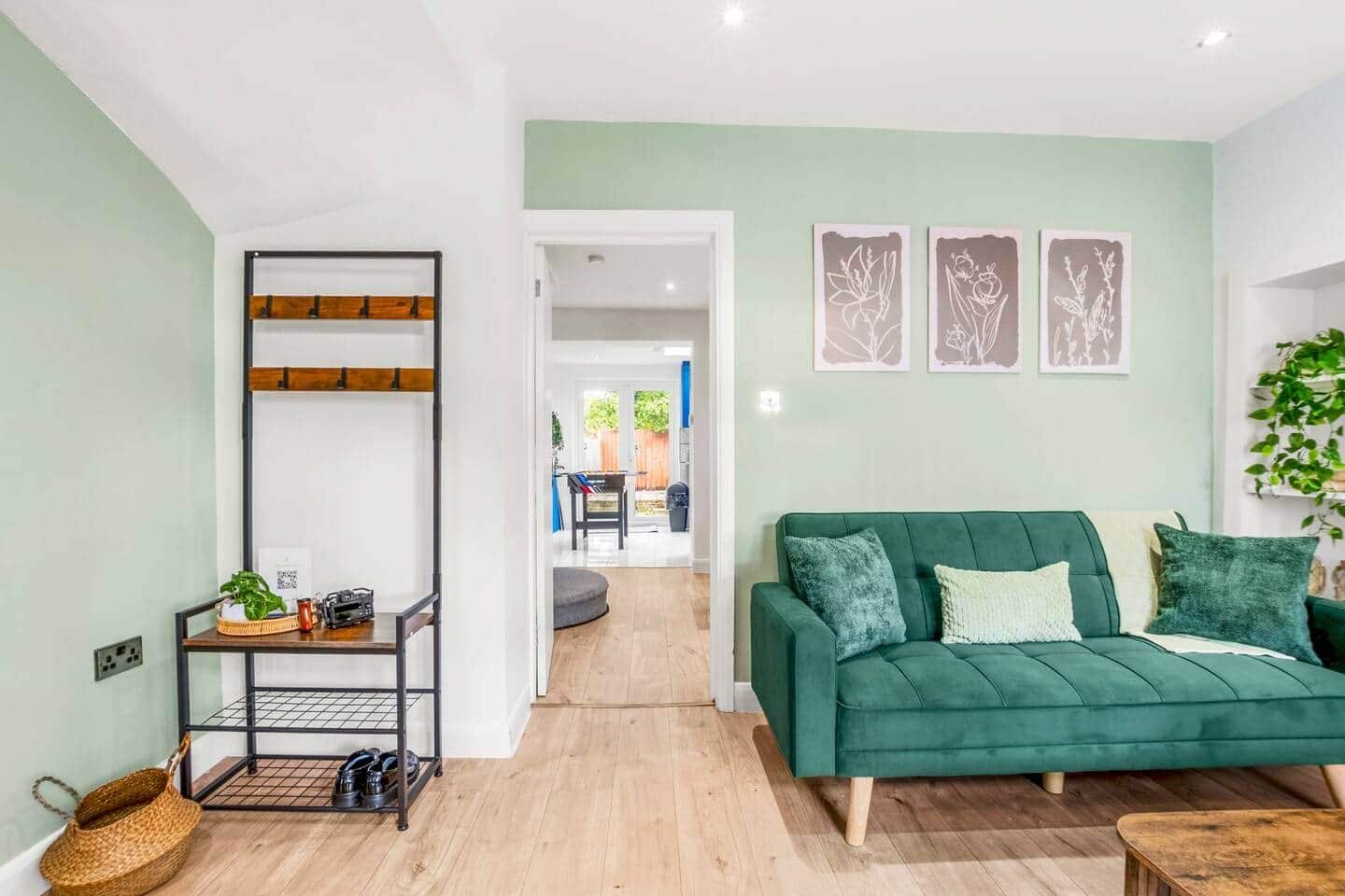 A modern living room with a green sofa, a coffee table, and a black metal shelf with items on it.