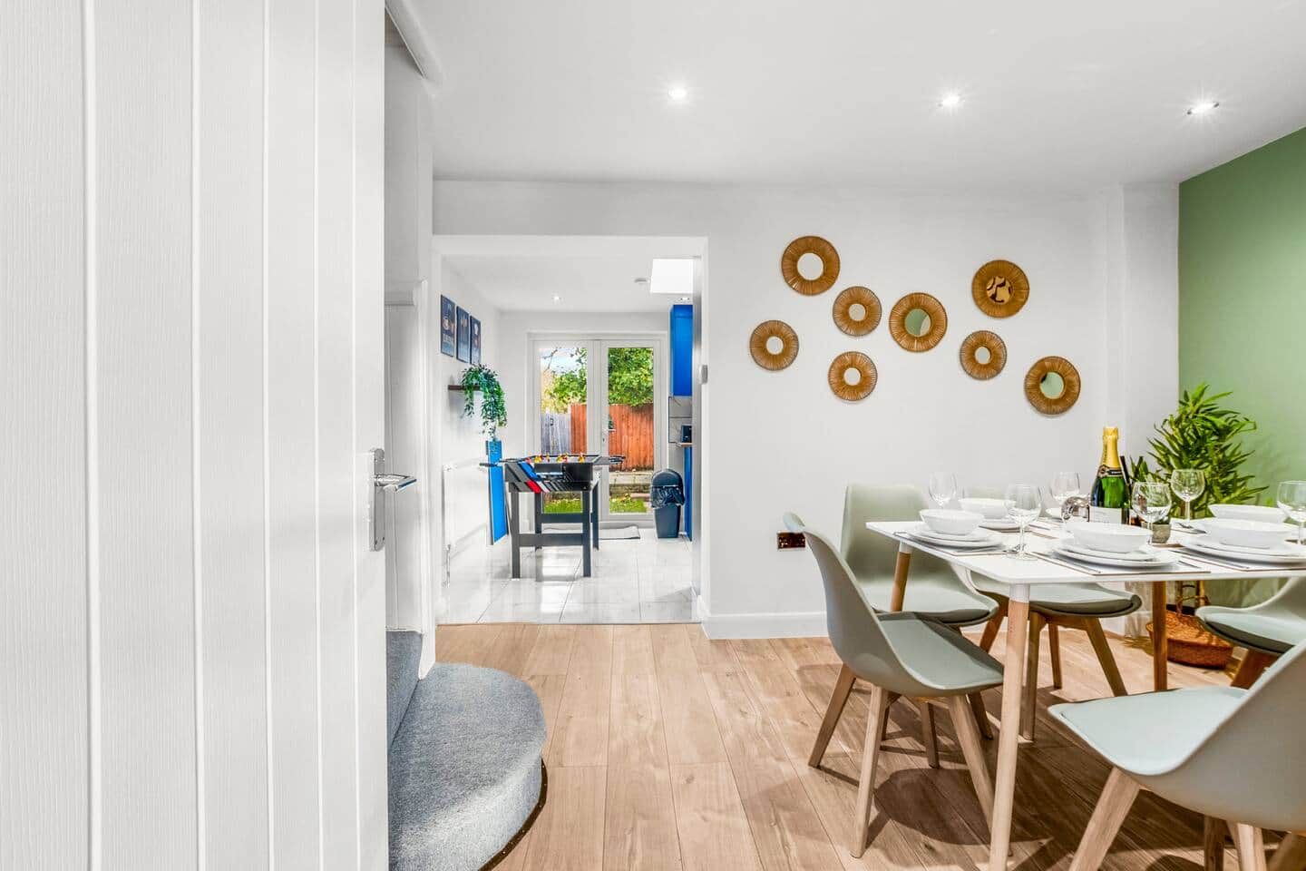 A modern dining area with a table set for four, a staircase leading to an outdoor area, and decorative wall art.
