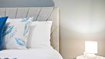 A neatly made bed with a headboard, a bedside lamp, and a decorative plate.