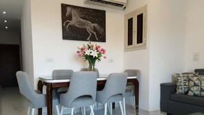 Ein moderner Essbereich mit Tisch und Stühlen, einer Blumenvase und einem Bild an der Wand.