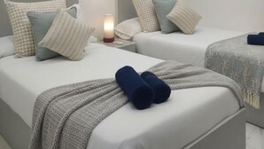 Ein Hotelzimmer mit zwei Betten, einem Bild an der Wand, einer Klimaanlage und einer Nachttischlampe.