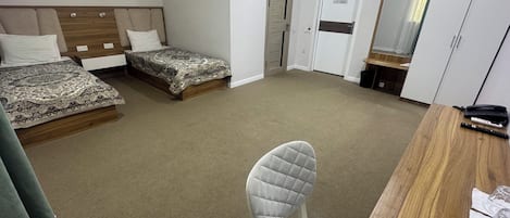 Une chambre d’hôtel avec deux lits, un bureau, une chaise et une armoire.