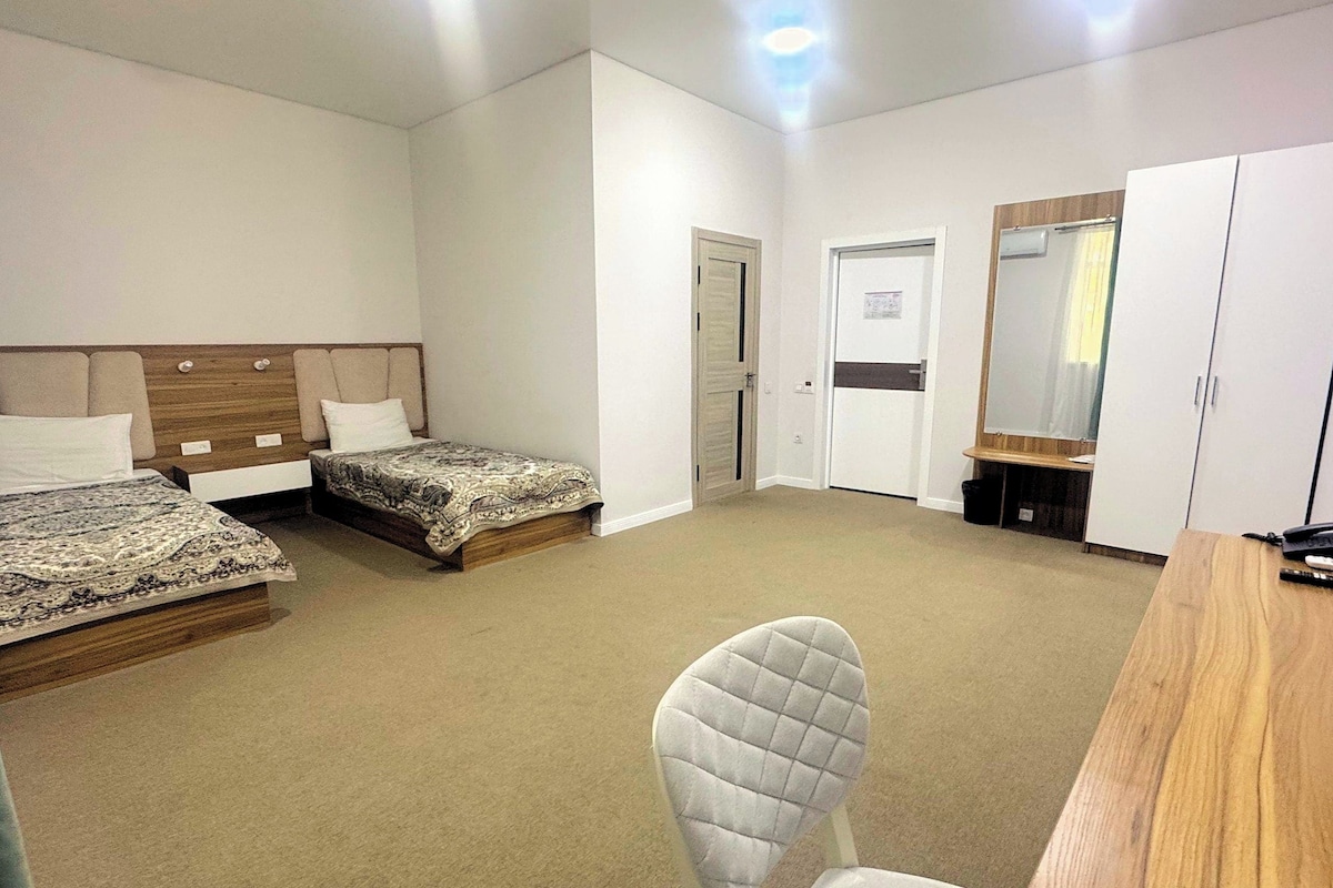 Habitación de hotel con dos camas, un escritorio, una silla y un armario.