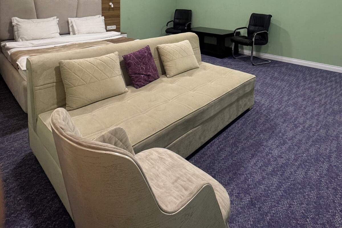 Une chambre d’hôtel avec un lit, un canapé, un bureau et deux chaises.