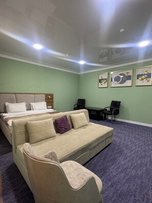 Une chambre d’hôtel avec un lit, un canapé, un bureau et deux chaises.