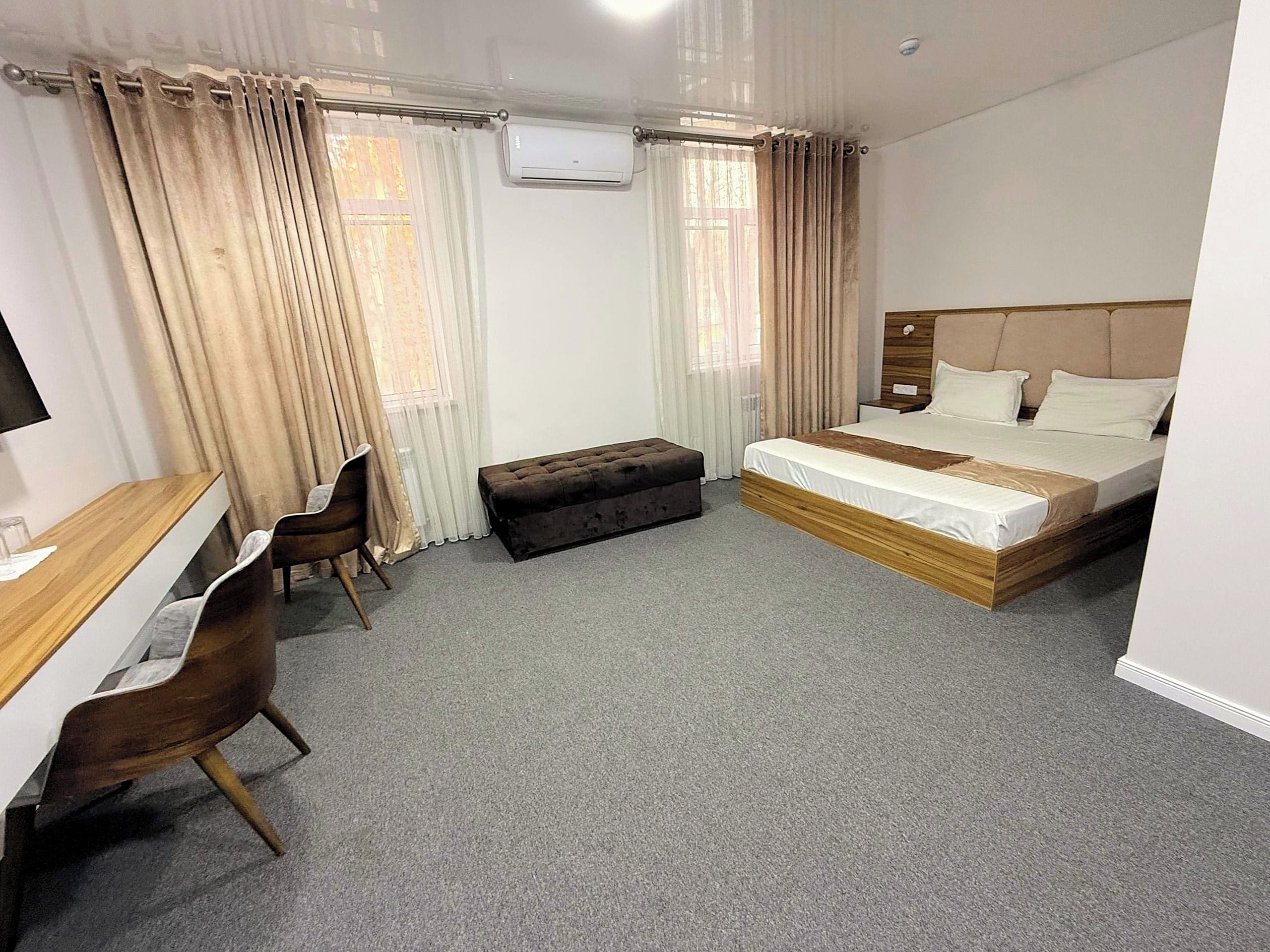 Ein Hotelzimmer mit Bett, Schreibtisch, Stuhl und einem fensterbepflanzten Fenster.