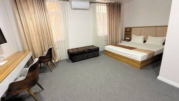 Une chambre d’hôtel avec un lit, un bureau, une chaise et une fenêtre avec des rideaux.