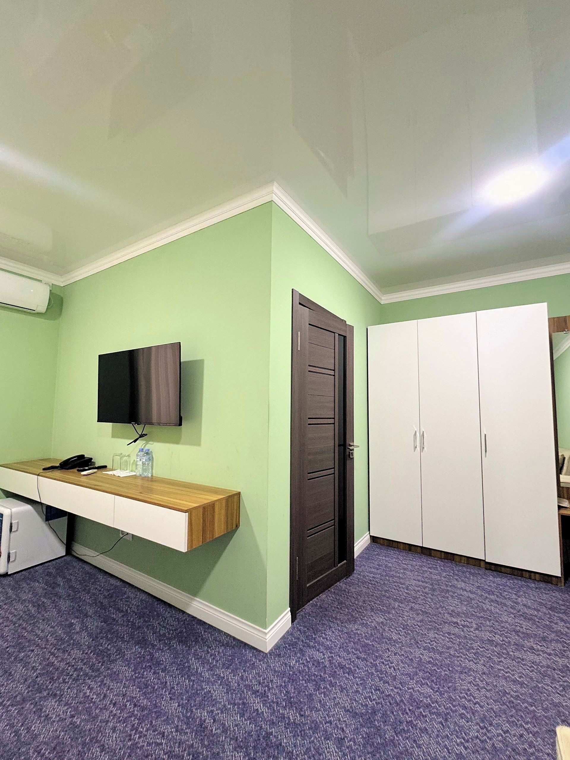 A room with a desk, a television, a wardrobe, and a door.