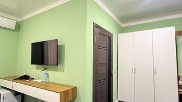 A room with a desk, a television, a wardrobe, and a door.