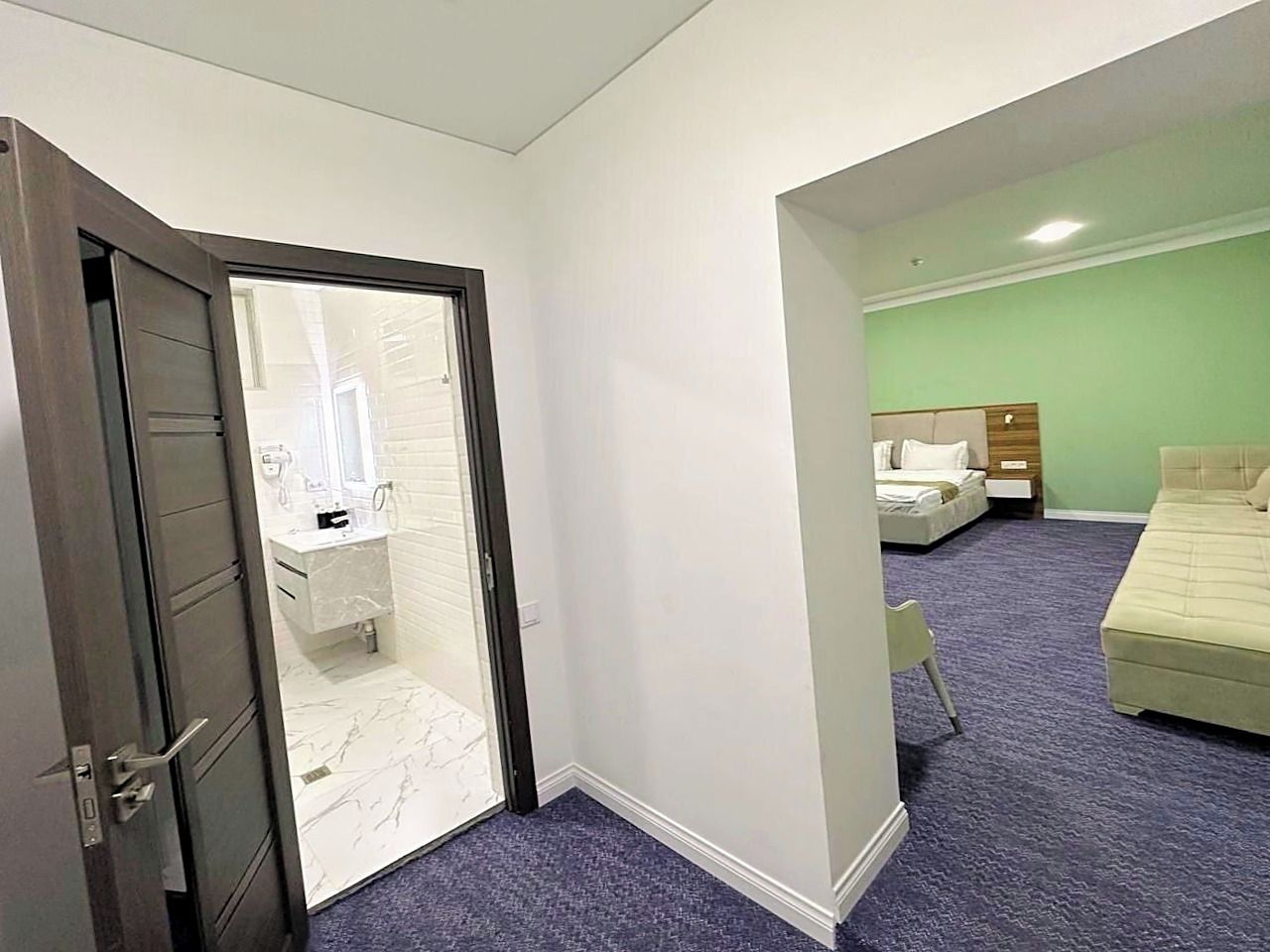 Une chambre d’hôtel avec salle de bain, un lit et un petit coin salon.