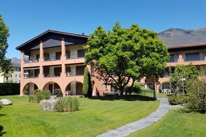 Ein mehrstöckiges Gebäude mit einem zentralen Innenhof, Bogenwegen und Außenbereichen mit Sitzgelegenheiten.