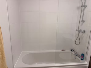 Ein Badezimmer mit einer Glaskabine, einer Badewanne, einer Duschbrause und einem Handduschausgang.