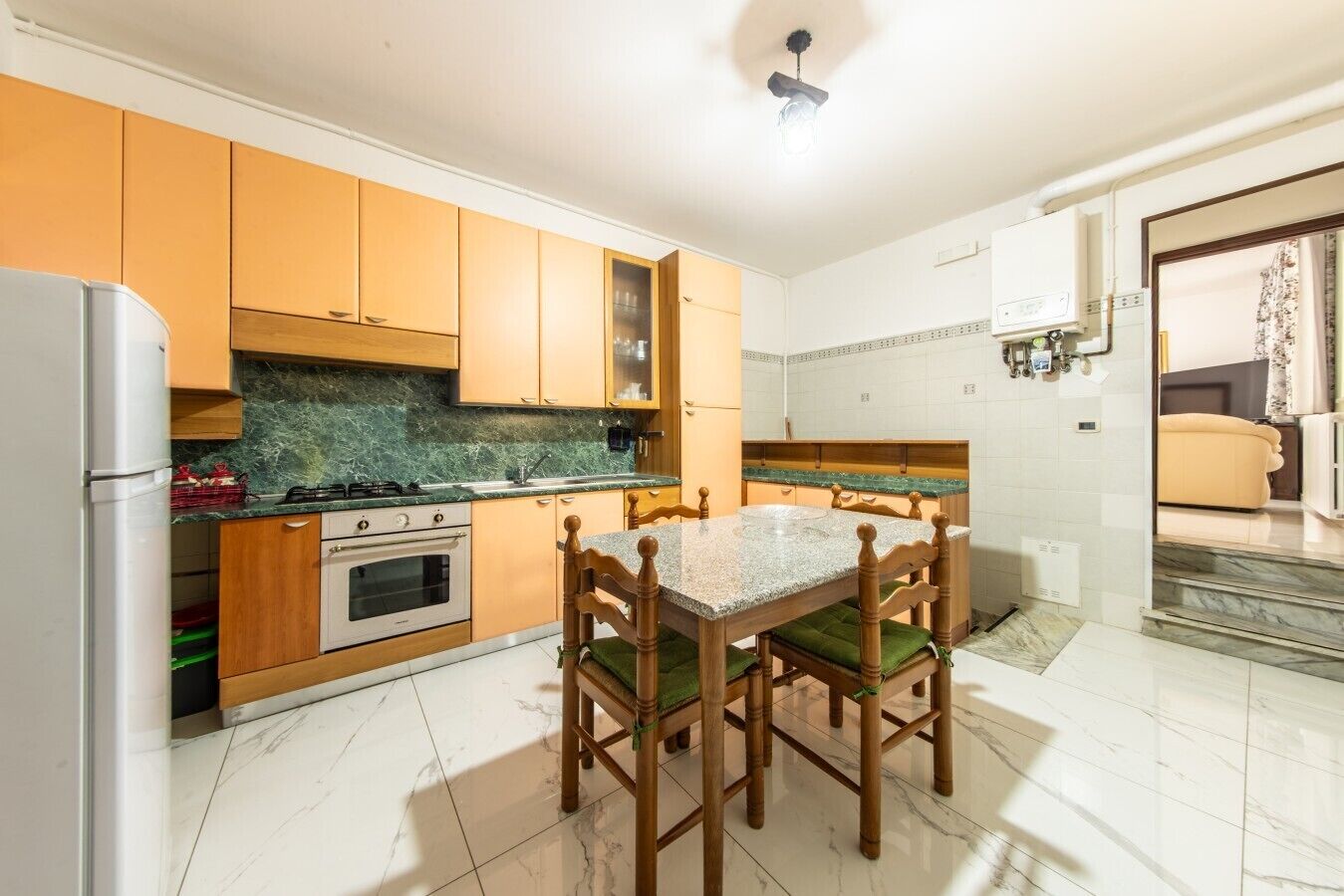 A kitchen with wooden cabinets, a granite countertop, a dining table with chairs, and a built-in oven.