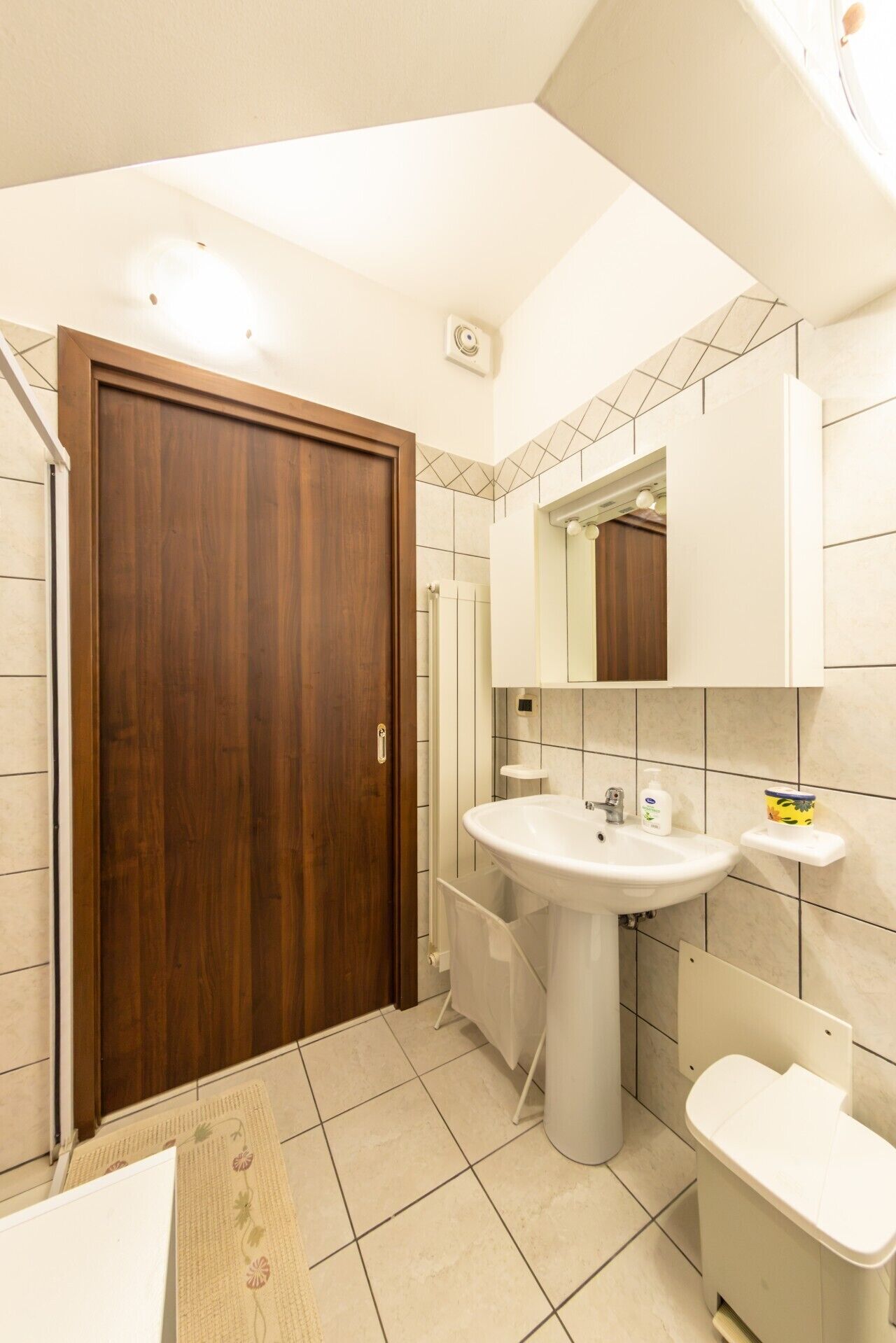 Une salle de bain avec une porte en bois, un lavabo, des toilettes et un miroir.