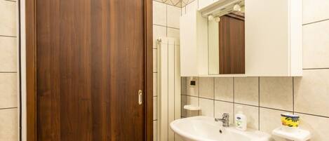 Une salle de bain avec une porte en bois, un lavabo, des toilettes et un miroir.
