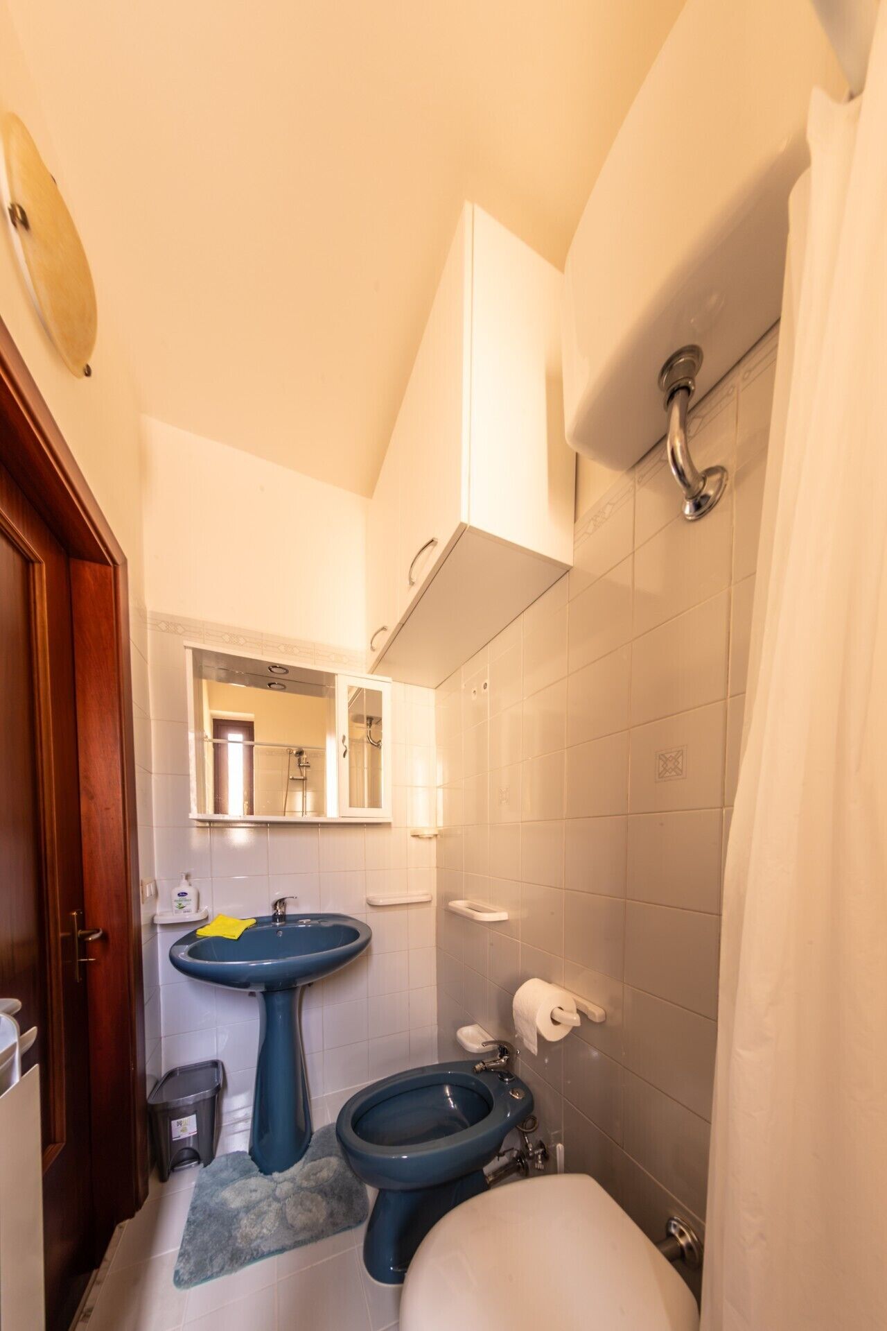 A compact bathroom with a pedestal sink, a toilet, and a shower.