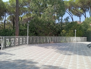 A paved walkway with a decorative metal railing, surrounded by trees and a clear sky. - Your private Mediterranean retreat in Sardinia (Santa Margherita di Pula)
