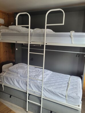 Ein Etagenbett mit zwei Schlafebenen, jeweils mit einer Matratze und Kissen.