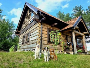 Una baita di legno con portico, una recinzione in legno e un'area erbosa.