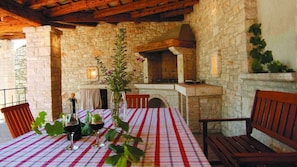 A stone-walled outdoor dining area with a checkered tablecloth, wooden chairs, and a wine glass set. - Villa Morus by Villas Guide (Svetvincenat)