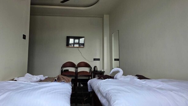 Habitación de hotel con dos camas, un escritorio, una silla, un televisor y un espejo.