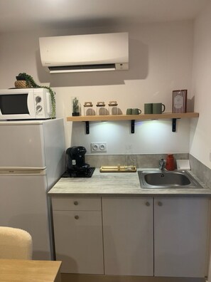 Et lille køkken med mikroovn, kaffemaskine og vask.