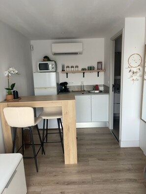 A compact kitchen with a wooden table and chairs, a microwave, and a coffee machine. - A Casarella di Lisa - Cozy studio with a terrace (Vescovato)