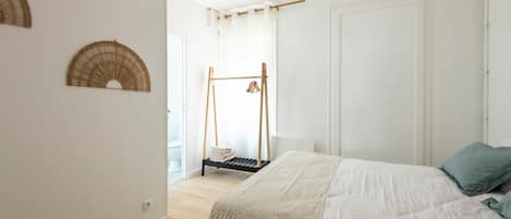 A bedroom with a bed, a hanging light fixture, and a wooden swing chair.