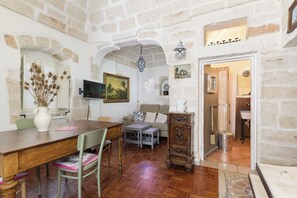 A rustic interior with a dining table, a sofa, a TV, and a wooden cabinet. - Terrazza Calipso by Wonderful Italy (Ostuni)