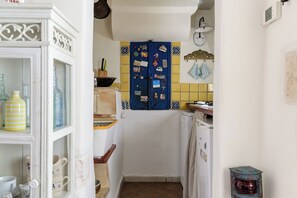 Eine schmale Küche mit einer blauen Tür, verziert mit verschiedenen Gegenständen, einem weißen Kühlschrank und einer gelben gefliesten Spritzschutzwand.