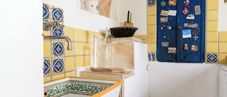A kitchen with a tiled backsplash, a sink, and a refrigerator.