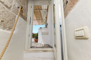 A narrow stairway leading to a door with a rope on the left and a light switch on the right. - Terrazza Calipso by Wonderful Italy (Ostuni)