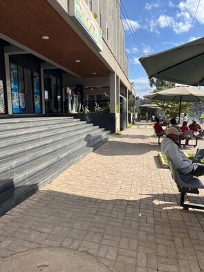 A building with a covered outdoor seating area, steps leading up to the entrance, and a clear sky. - Aido Studio at Tsavo Fedha | Near JKIA,SGR And EASA. (Nairobi)