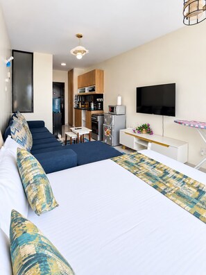 A modern hotel room with a large bed, a TV, a kitchenette, and a seating area. - Aido Studio at Tsavo Fedha | Near JKIA,SGR And EASA. (Nairobi)